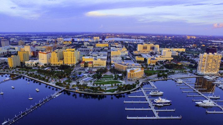 An aerial view of the skyline of West Palm Beach, Florida, at sunset with boats at the harbor.