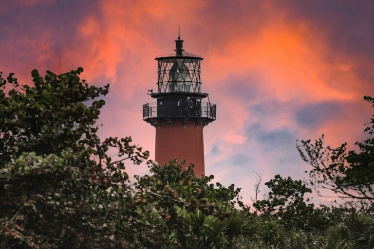 Jupiter, FL lighthouse at sunset with trees.
